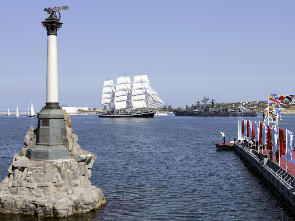 The Russian Black Sea naval headquarters at Sevastopol, Crimea, in 2008. In the background on the right is a Russian destroyer. The Russian tall ship Padalla (with white sails) is in the center. In the foreground is the Monument to Scuttled Ships, marking Russia's intentional destruction of its own naval fleet in the Crimean War in 1854 as British and French warships approached.