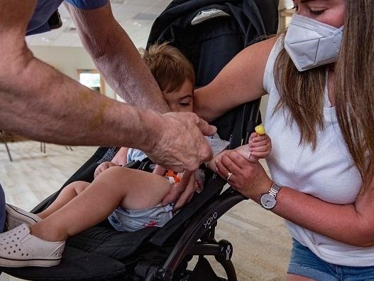 A mother holds her 1-year-old son as he receives the child Covid-19 vaccine in his thigh at Temple Beth Shalom in Needham, Mass., on June 21, 2022. The temple was one of the first sites in the state to offer vaccinations to anyone in the public.