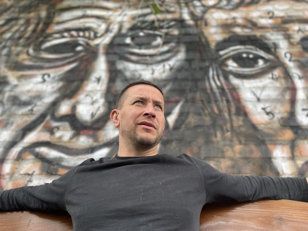 Vladyslav Krasnoshchok sits in front of one of the many murals he's painted in his garden outside his home in Kharkiv, Ukraine.