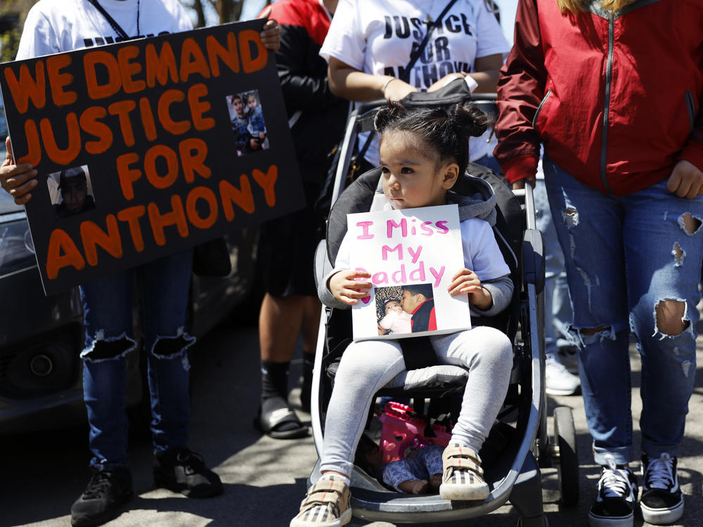 In this May 1, 2021, photo, Ailani Alvarez, 2, the daughter of Anthony Alvarez, who was shot by the police, holds a sign reading 