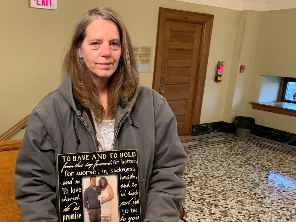 Jenny Boever, Joe Boever's widow, stands in the South Dakota state Capitol on April 12, 2022 holding a photo taken on their wedding day. She was at the capitol for the impeachment proceedings of Attorney General Jason Ravnsborg.