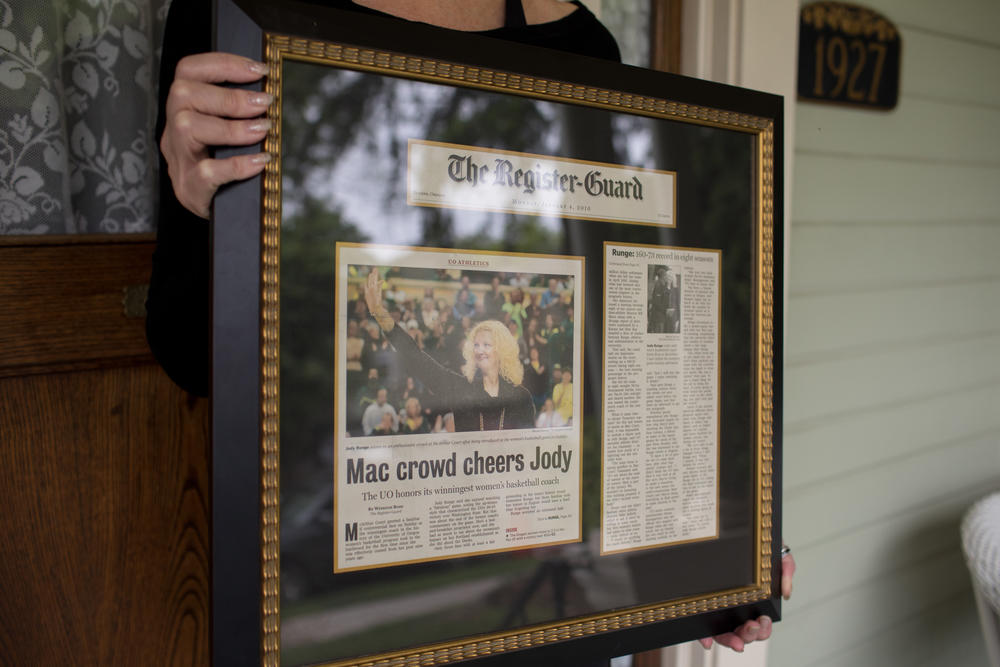 Runge holds a framed newspaper article about returning to UO for the closing of McArthur court.