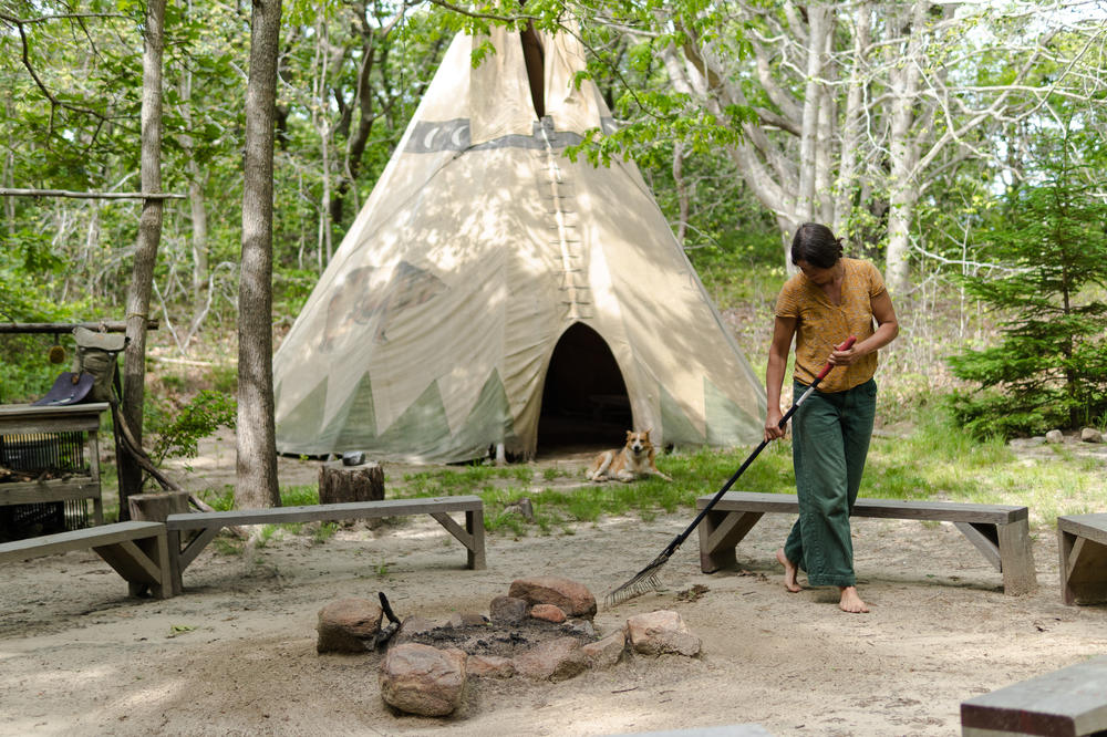 Audrey Van Der Krogt, rakes sand by a fire pit to prepare for an employee fire-making training at Sassafras Earth Education.