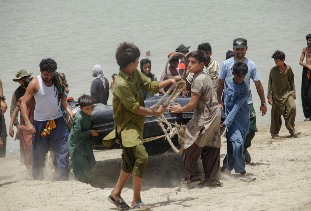 Men and boys from a nearby village help carry one of the expedition's rubber dinghies out of the river.