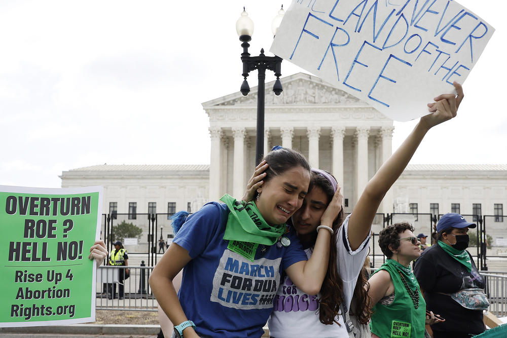Abortion rights activists Carrie McDonald (L) and Soraya Bata react to the Dobbs v. Jackson Women's Health Organization ruling which overturns Roe v. Wade.
