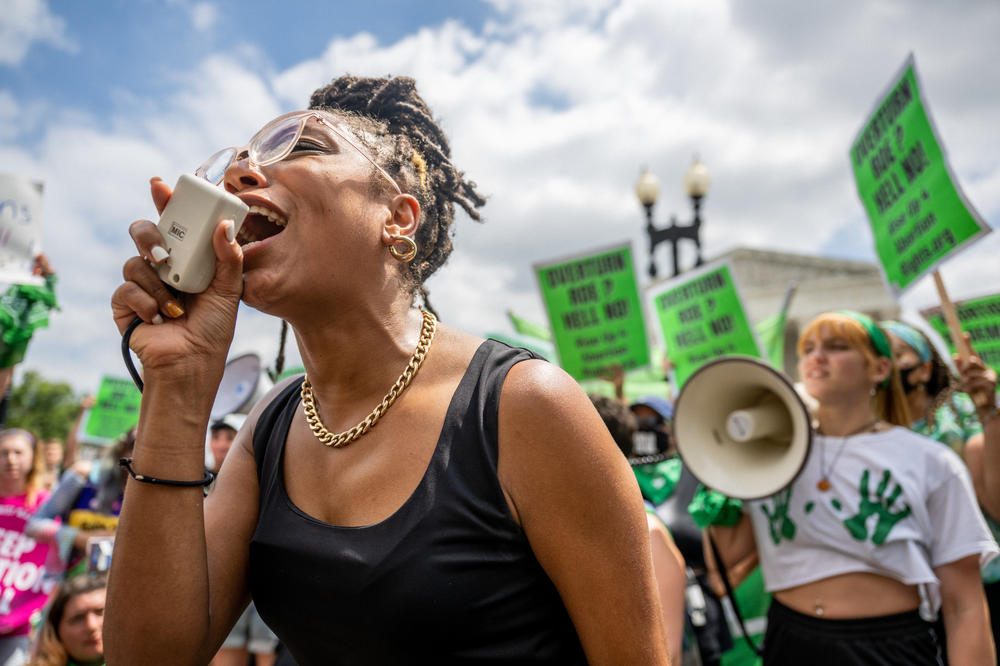 Abortion rights demonstrator Elizabeth White leads a chant in response to the <em>Dobbs v. Jackson Women's Health Organization</em> ruling in front of Supreme Court on Friday.