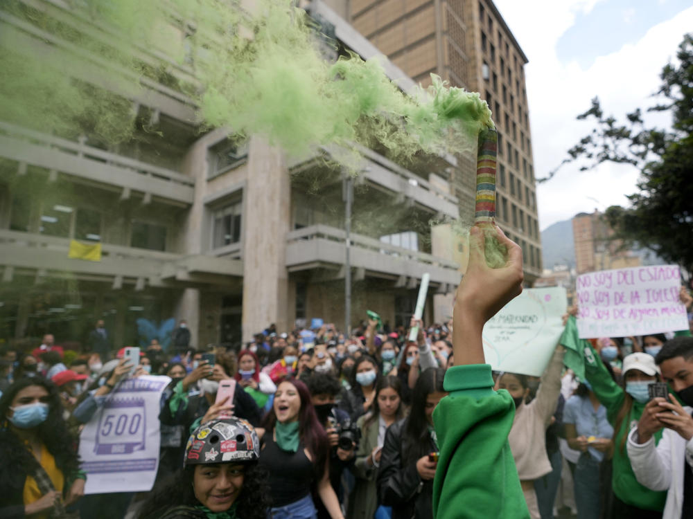 An abortion-rights activist holds up a flare outside the Constitutional Court in Bogotá, Colombia, in February. The court later ruled that people can get abortions until the 24th week of pregnancy without any permits from lawyers or doctors.