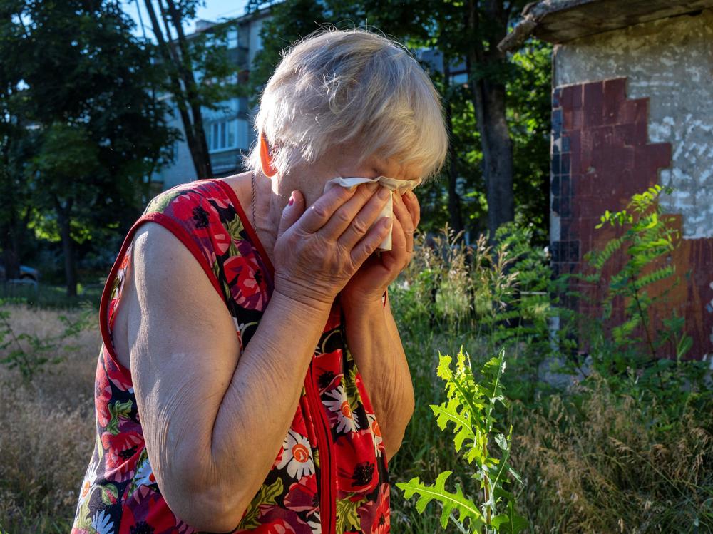 A woman reacts as rescuers evacuate the body of her husband, who was killed in a rocket attack on a residential area in Kharkiv on Monday. The head of Kharkiv's regional administration said a Russian strike on Ukraine's second-largest city killed at least four people and wounded 19 others, including four children.