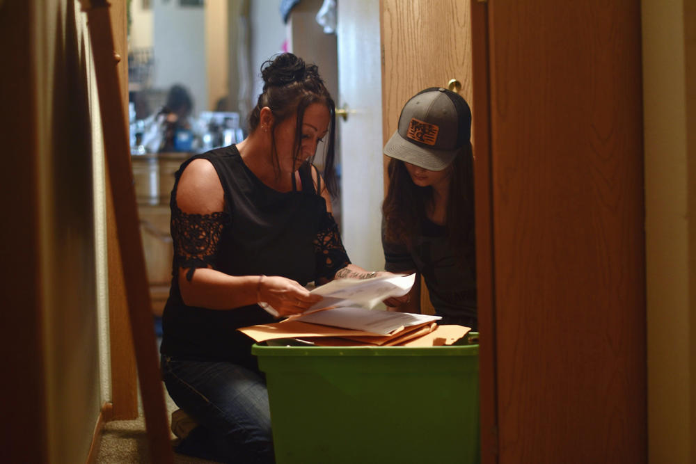 As her daughter Daisyauna watches, Daisy Hohman sifts through paperwork from the time her children were placed in foster care. Hohman says having to pay her Minnesota county was an added stress in her life: 