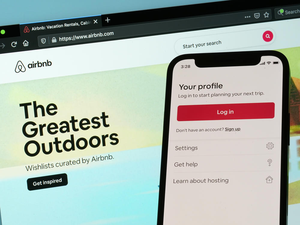 The login page for Airbnb's iPhone app is seen in front of a computer displaying Airbnb's website, Saturday, May 8, 2021, in Washington.