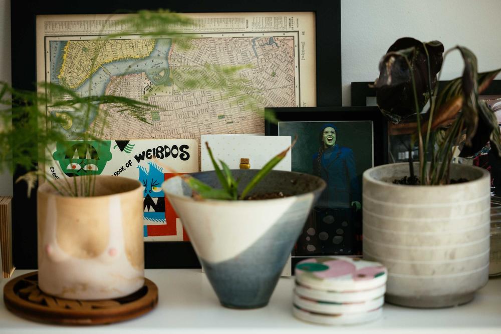 A photo of Stickler as Elphaba in <em>Wicked</em> sits next to a framed map of New York City in Stickler's home in Chicago. Now a software engineer, Stickler previously worked as a Broadway performer.