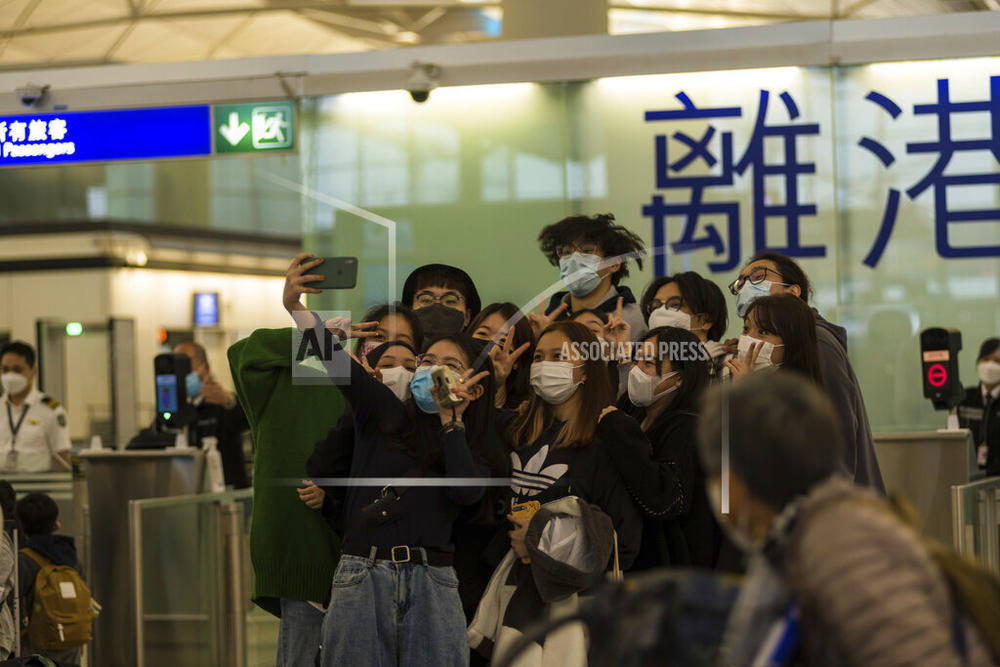 Travelers and friends pose for a selfie before entering the immigration area of the departure hall in the Hong Kong International Airport on April 2, 2022.