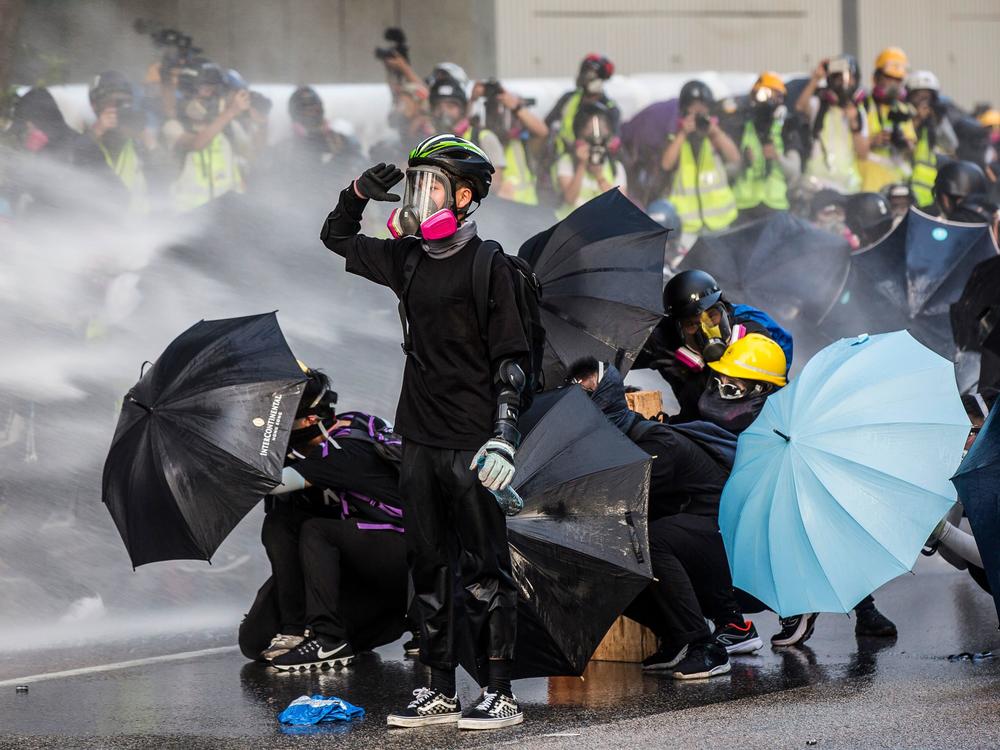 Pro-democracy protesters react as police fire water cannons outside the government headquarters in Hong Kong on September 15, 2019.