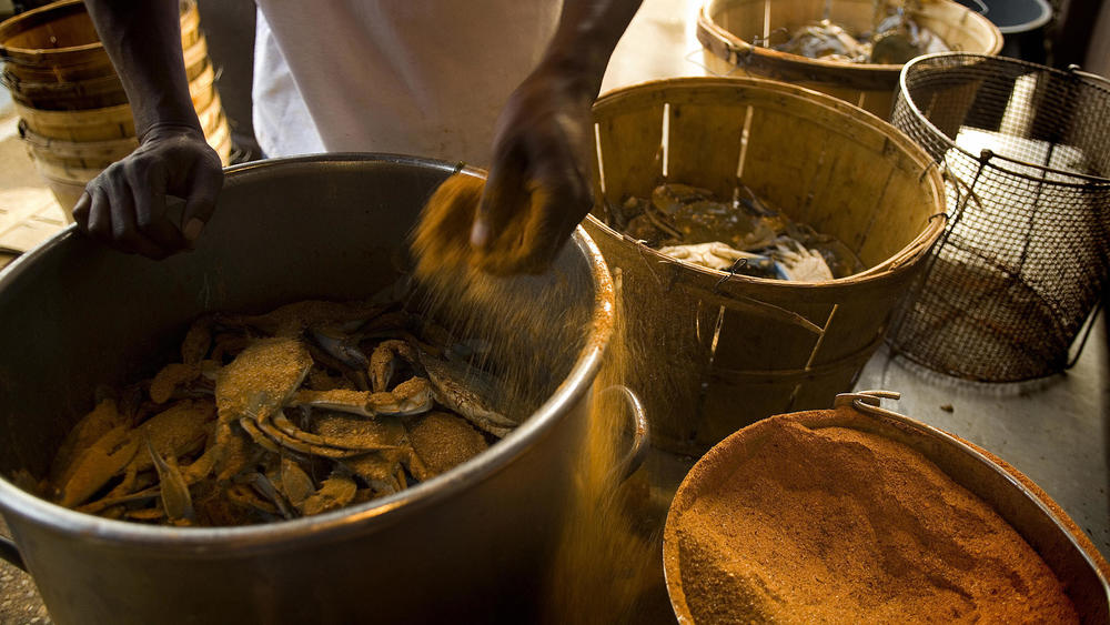 A chef puts Old Bay seasoning on blue crabs in Maryland.
