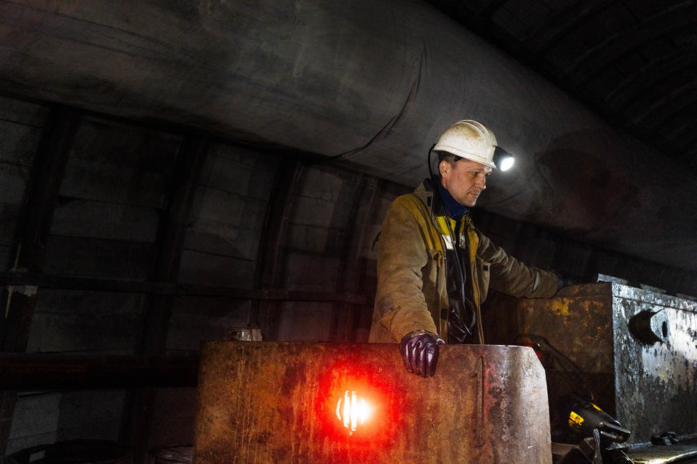 An operator of the mine railway that carries people in and out of the depths of the mine waits as workers disembark.