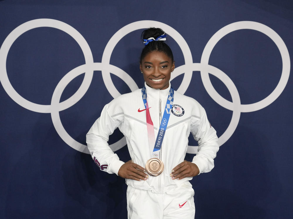Simone Biles poses wearing her bronze medal from balance beam competition during artistic gymnastics at the Summer Olympics on Aug. 3, 2021, in Tokyo. President Biden will present the Presidential Medal of Freedom to Biles and 16 others at the White House next week.