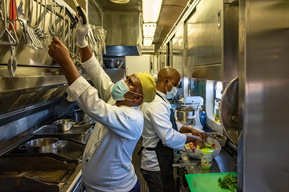Chef Nangamso Gwiliza reaches for a utensil in the kitchen of the Phelophepa in Thaba Nchu, South Africa. Operating out of a tiny space in carriage No. 5, Gwiliza and his team cook over 100,000 meals per year for the train's staff and contractors.