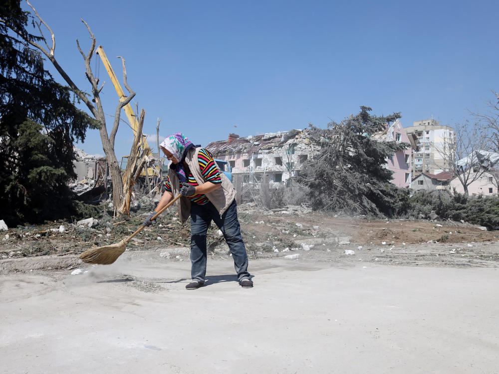 A woman cleans the area in front of a building hit by a missile strike in the Ukrainian town of Serhiivka, near Odesa, on Friday. The attack killed at least 18 people and injured 30.