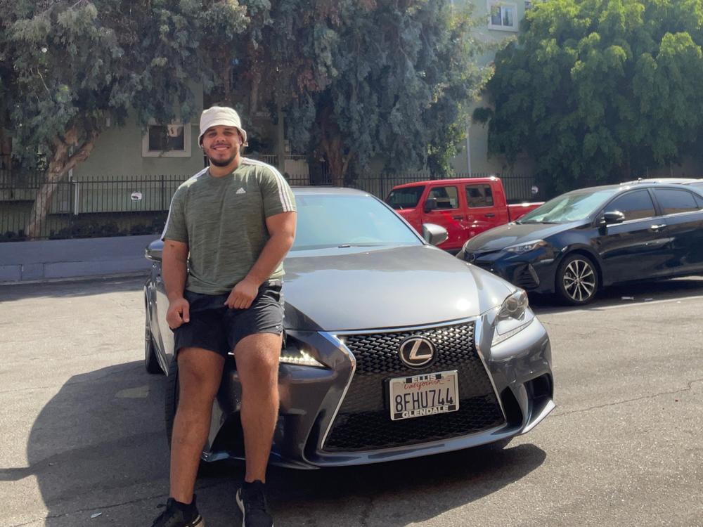 Johnny Navarro sits on the hood of his recently purchased 2014 Lexus.