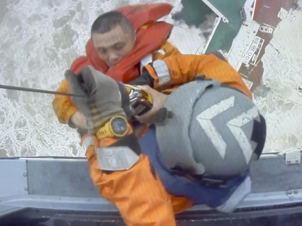 Helicopter crew members winch up a man from a sinking ship in the South China Sea on Saturday as a storm was moving in the area.