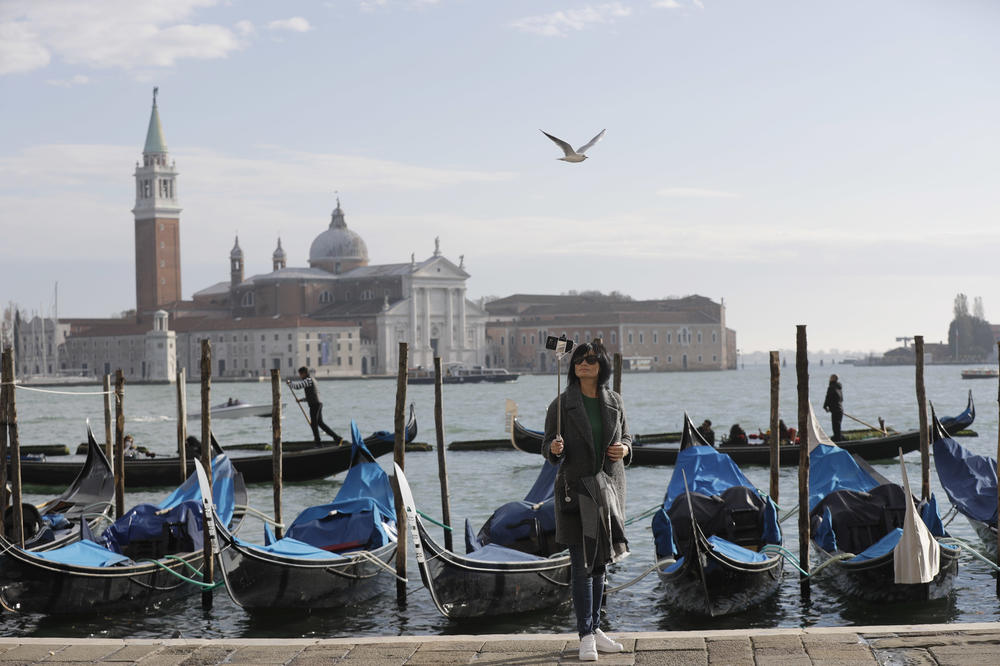 A tourist takes a selfie in St. Mark's Square in Venice, Italy, in 2016. Starting in January, the city will require day-trippers to make reservations and pay a fee to visit.
