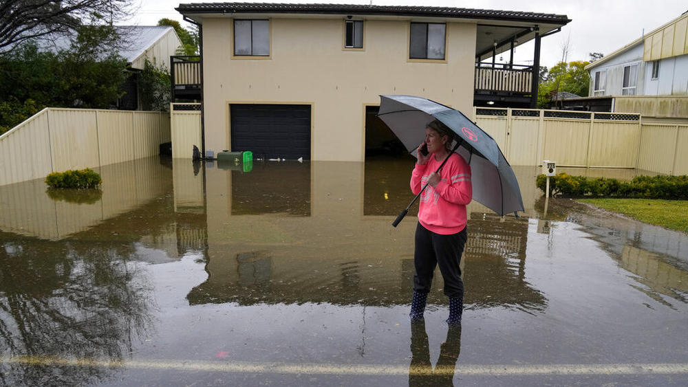 A woman stands in a flooded street Tuesday at Windsor on the outskirts of Sydney, Australia.