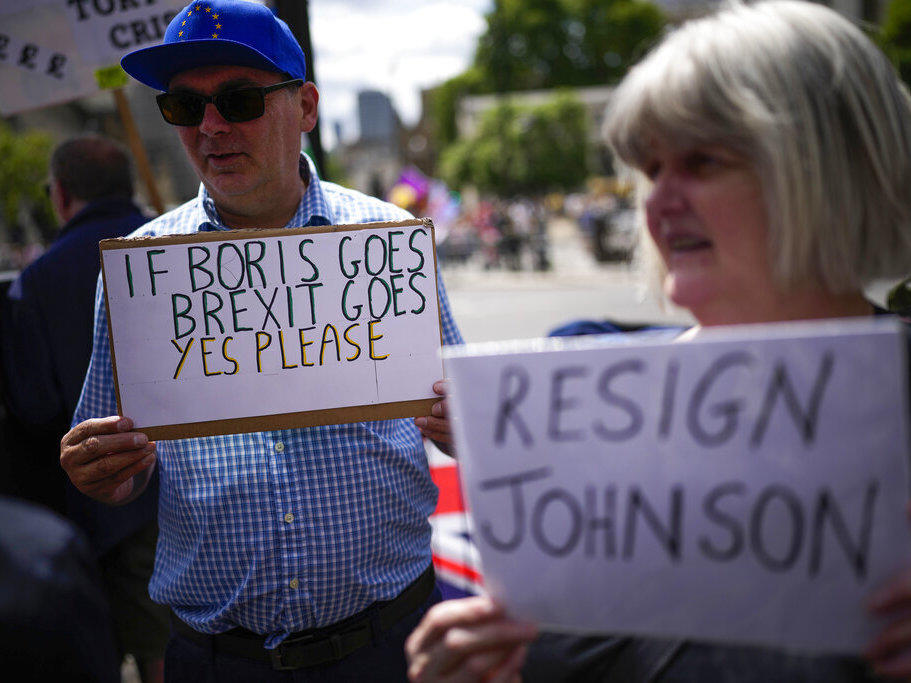 People holds signs as they protest Wednesday outside the Houses of Parliament in London.