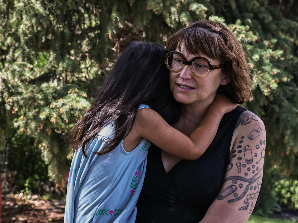 Jeni Rae Peters and daughter embrace at their home in Rapid City, S.D. In 2020, Peters was diagnosed with stage 2 breast cancer. After treatment, Peters estimates that her medical bills exceeded $30,000.