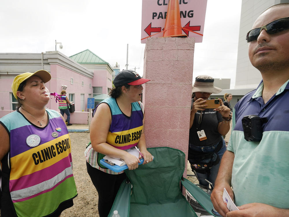 Clinic escorts use party horns and whistles to counter the presence of anti-abortion activist Gabriel Olivier, right, outside the Jackson Women's Health Organization clinic in Jackson, Miss., on July 6, 2022.