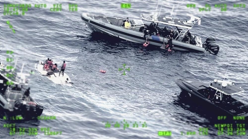 People stand on a capsized boat, left, as some of its passengers are pulled up on to a rescue boat, top, May 12 in the open waters northwest of Puerto Rico.