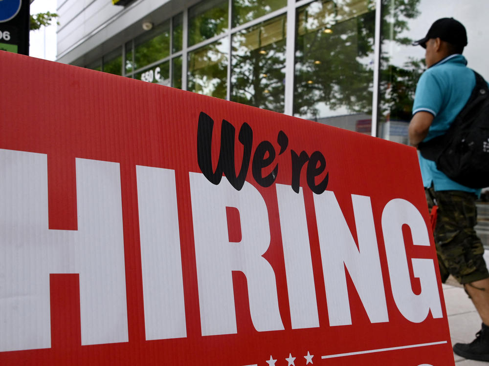 Fewer jobs were added in June, but the labor market is still tight. A man walks past a 