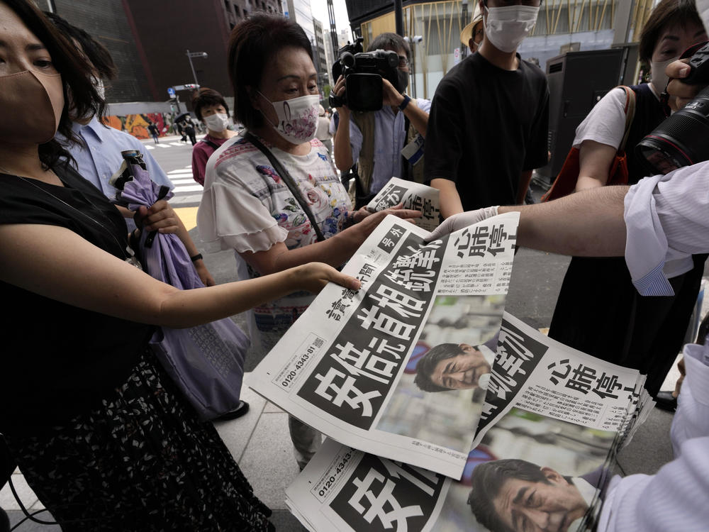 An employee of the Yomiuri Shimbun distributes extra editions of the newspaper in Tokyo with reporting on the shooting of Japan's former Prime Minister Shinzo Abe on Friday.