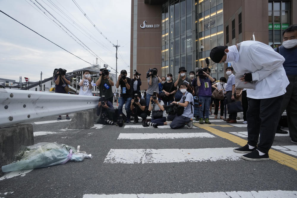 A man prays after putting a bouquet of flowers at a makeshift memorial at the scene where former Japanese Prime Minister Shinzo Abe was shot to death while delivering a speech in support of a Liberal Democratic Party candidate at a political event in Nara, Japan, on Friday.