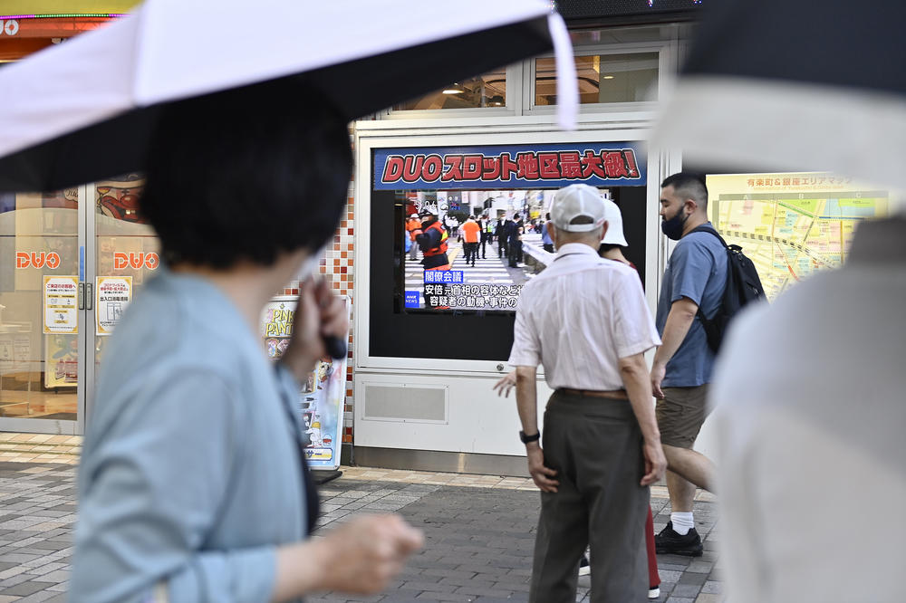 People on the street watch a TV broadcasting news about Shinzo Abe, the former prime minister of Japan, who was fatally shot  while campaigning for a Liberal Democratic Party candidate at a gathering in Nara, Japan, on Friday.