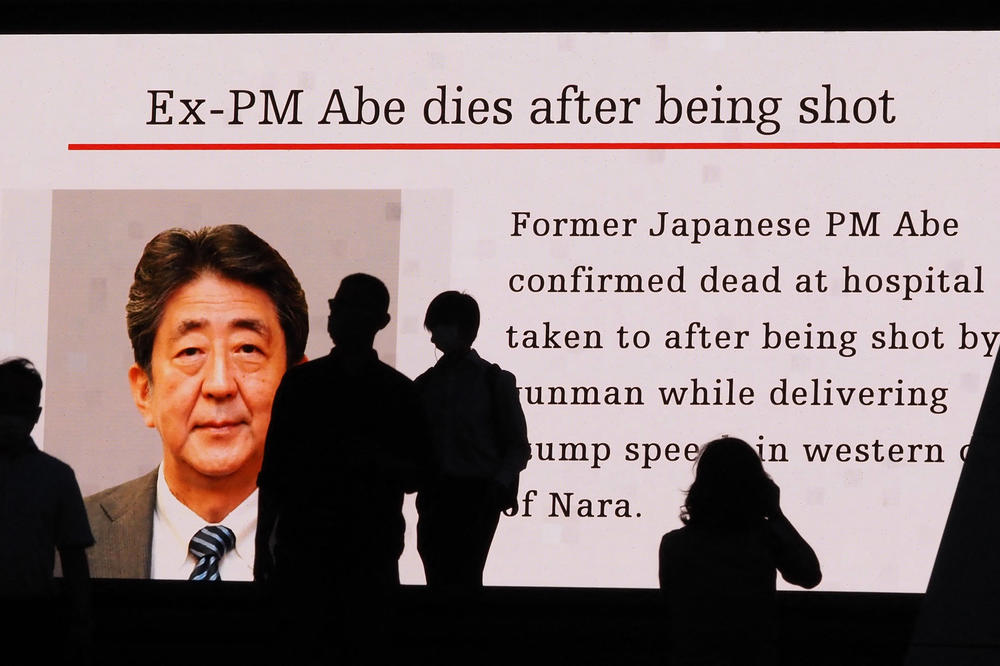 Pedestrians are silhouetted against a large public video screen showing an image of former Japanese Prime Minister Shinzo Abe in the Akihabara district of Tokyo on Friday after he was shot and killed in the city of Nara.