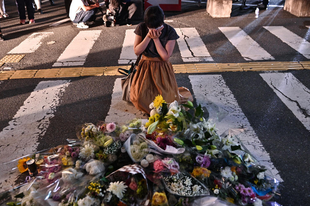 A woman reacts in front of a makeshift memorial outside Yamato-Saidaiji Station in Nara, a city in western Japan, where former Japanese Prime Minister Shinzo Abe was shot and killed while speaking at a political event Friday.