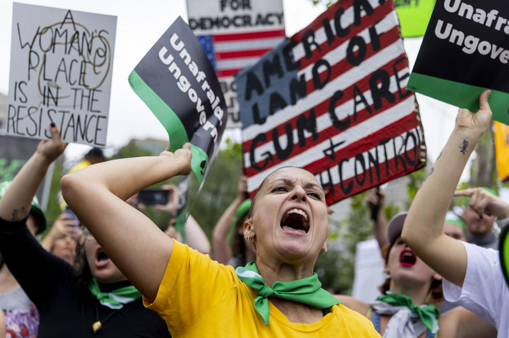 Ashley Taylor, from Augusta, GA, with yellow shirt and green bandana around her neck, chants at the rally.