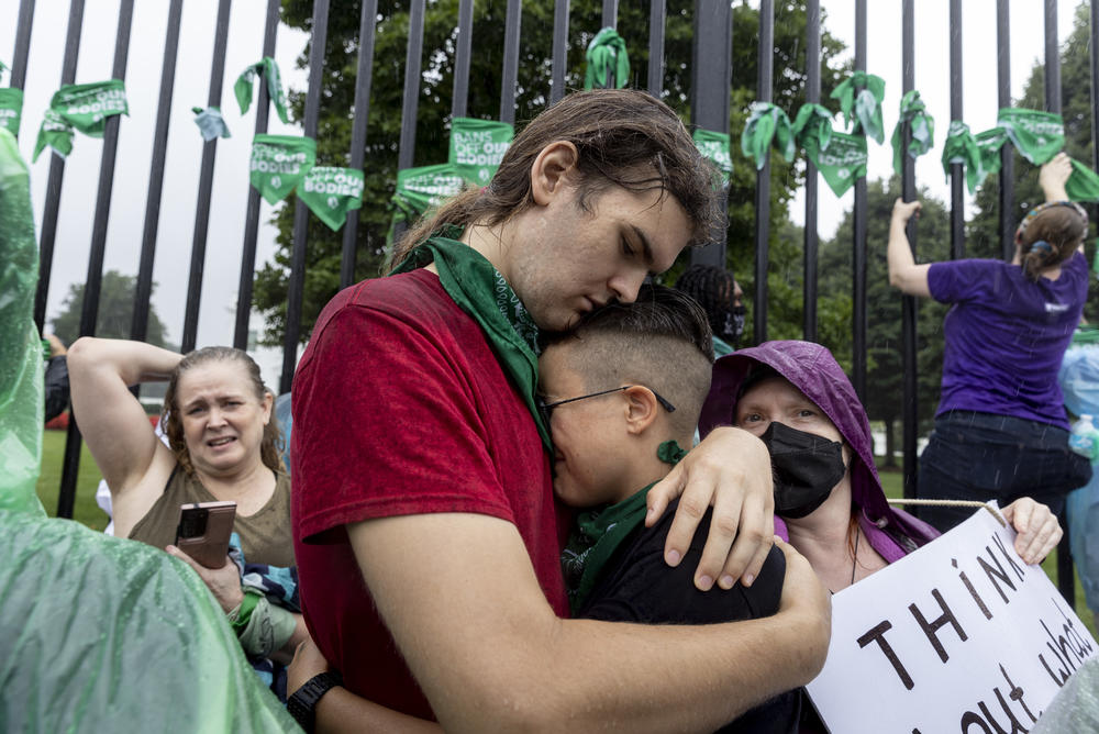 Demonstrators embrace in front of the White House as the march arrives.