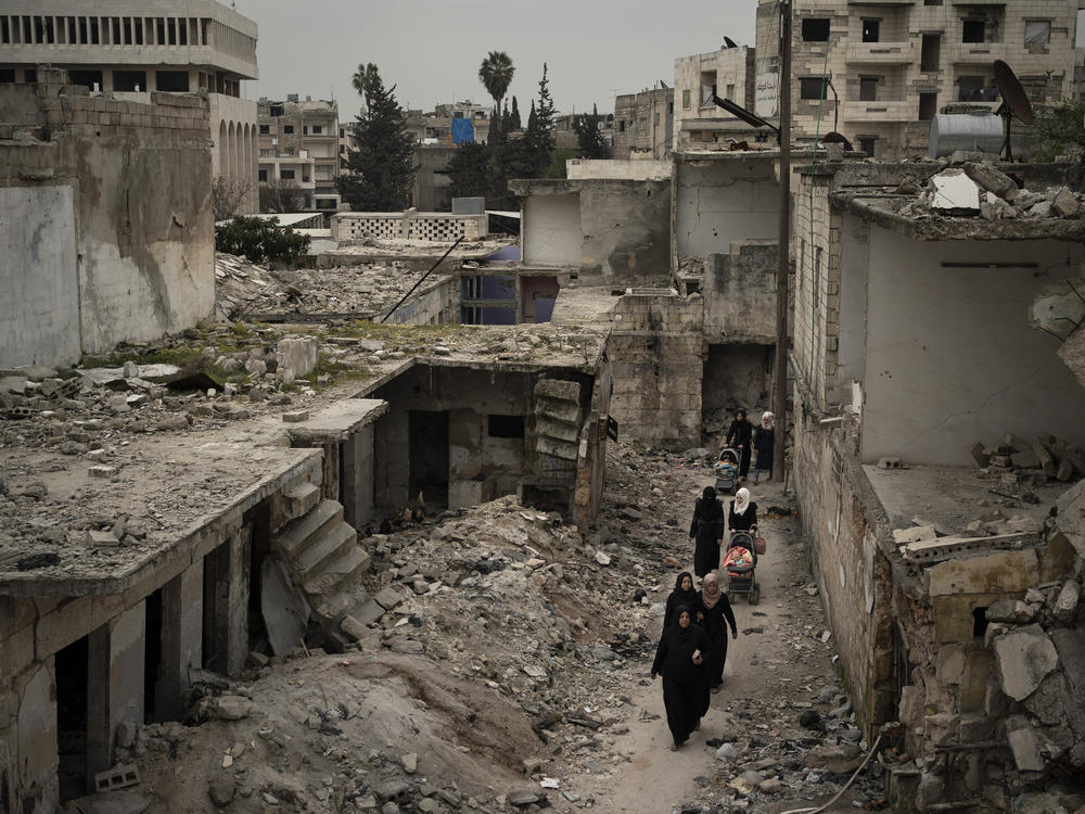 Women walk in a neighborhood heavily damaged by airstrikes in Idlib, Syria, on March 12, 2020.