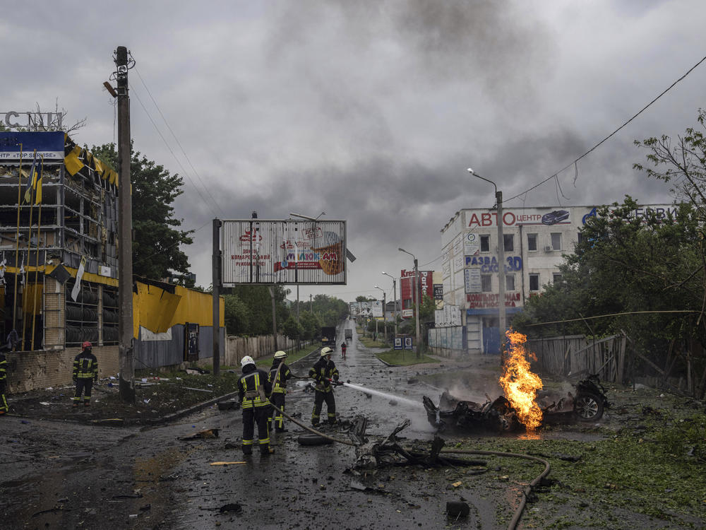 Rescue workers put out the fire of a destroyed car after a Russian attack in a residential neighborhood in downtown Kharkiv, Ukraine, on Monday.