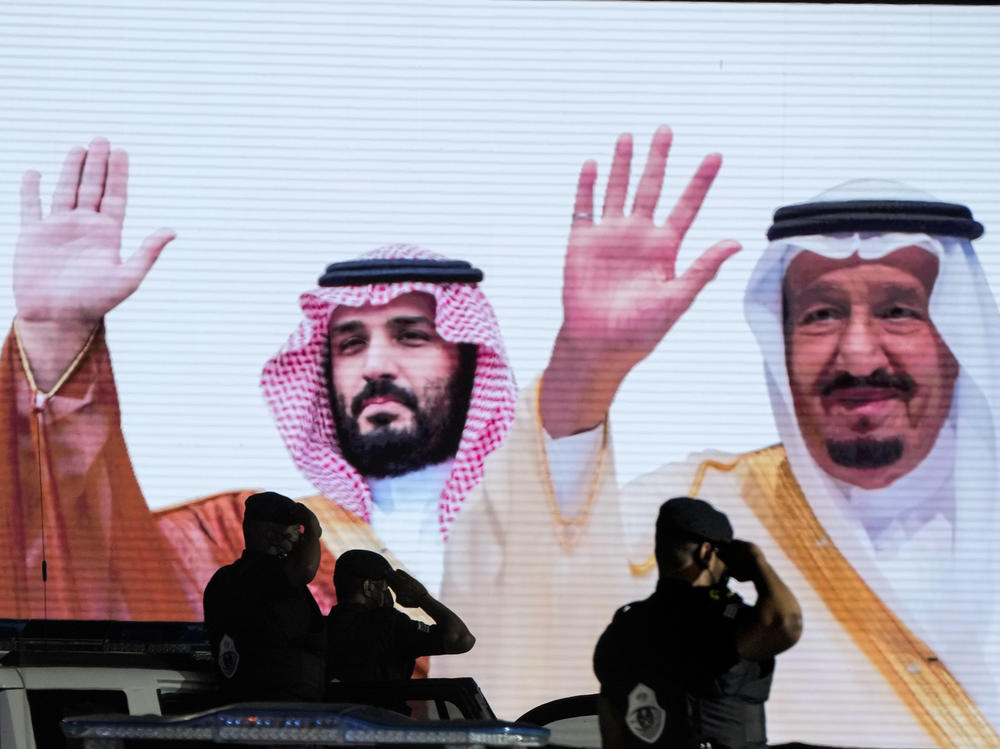 Saudi special forces salute in front of a screen displaying images of Saudi King Salman (right) and Crown Prince Mohammed bin Salman on July 3. President Biden's visit to the Middle East this week includes meeting with both.
