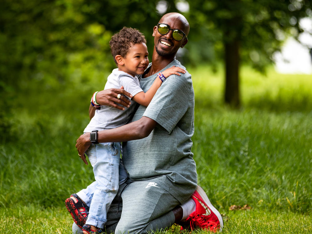 Mo Farah and his son, Hussein, embrace in 2018 as they play in St. James' Park in London, England. Farah says he's known under a false name, and that his real name is Hussein Abdi Kahin.