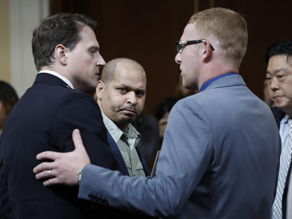 Stephen Ayres, right, who entered the Capitol during the riot, shakes hands with Washington Metropolitan Police Department officer Daniel Hodges, left, as Capitol Police Sgt. Aquilino Gonell, center, watches at the conclusion of Tuesday's hearing.