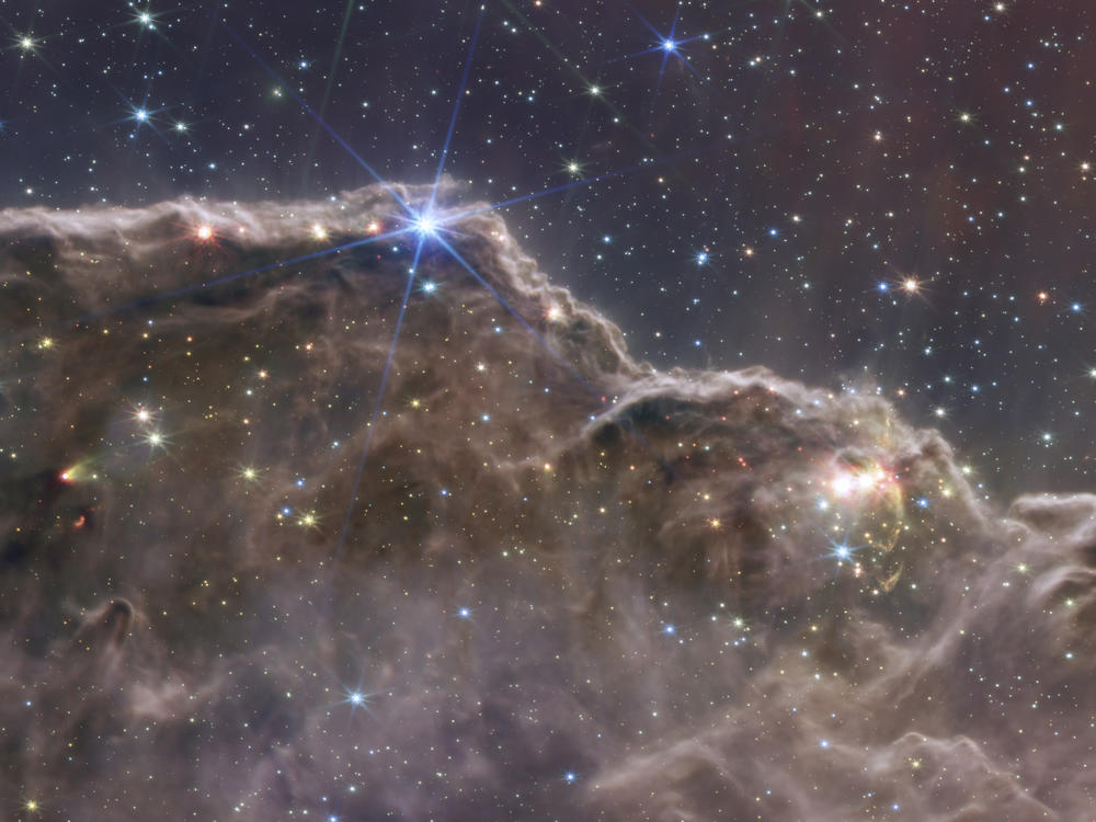 This image released by NASA on Tuesday, July 12, 2022, combined the capabilities of the James Webb Space Telescope's two cameras to create a never-before-seen view of a star-forming region in the Carina Nebula. Captured in infrared light by the Near-Infrared Camera (NIRCam) and Mid-Infrared Instrument (MIRI), this combined image reveals previously invisible areas of star birth.