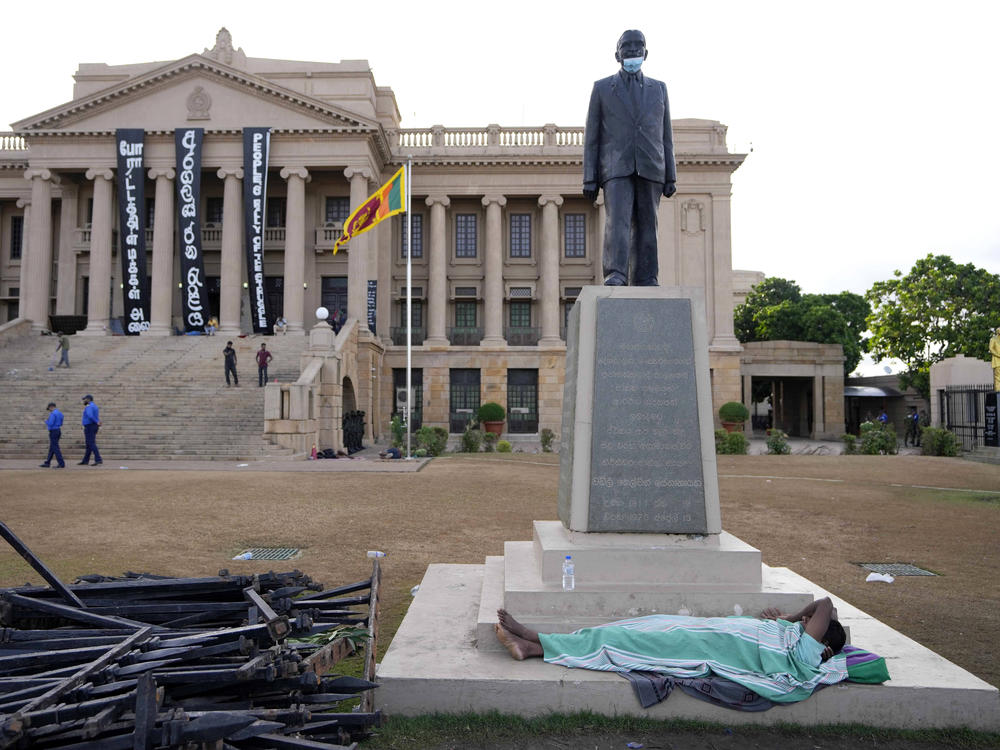 A protester sleeps under a statue in the compound of presidential secretariat in Colombo, Sri Lanka, Friday, July 15, 2022.