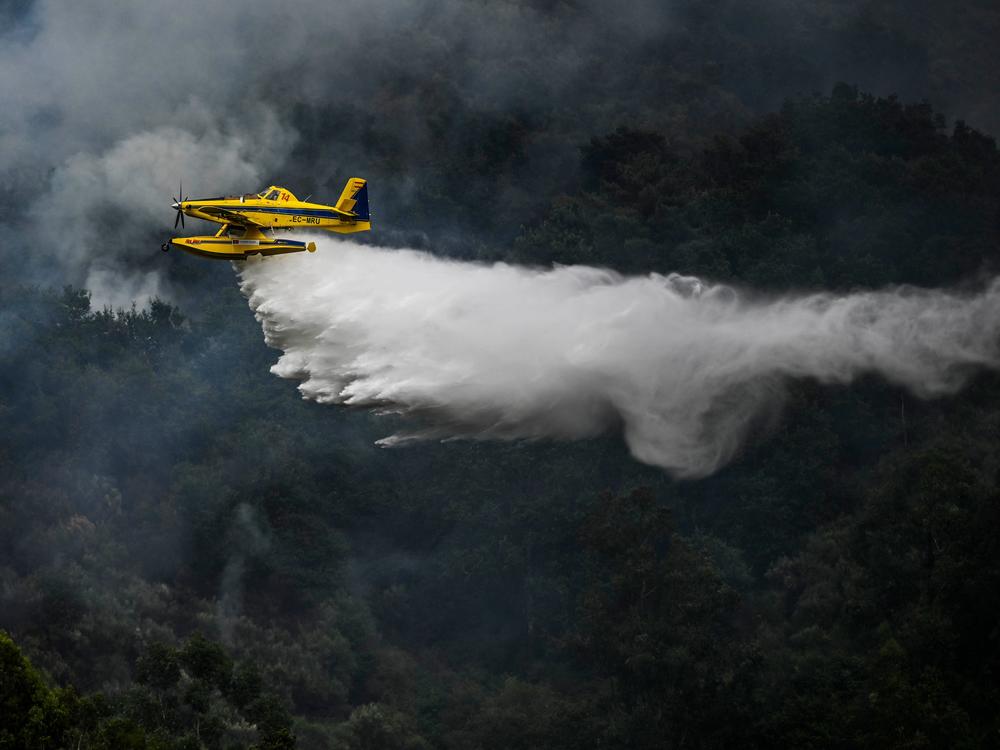 A firefighter aircraft drops water in a wildfire in Portugal on Saturday.