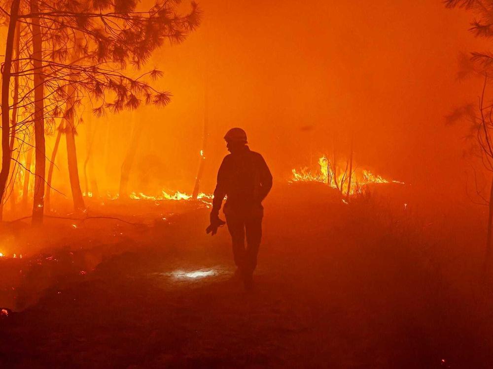 This photo provided by the fire brigade of the Gironde region (SDIS 33) shows firefighters fighting wildfire near Landiras, southwestern France, Sunday July 17, 2022.
