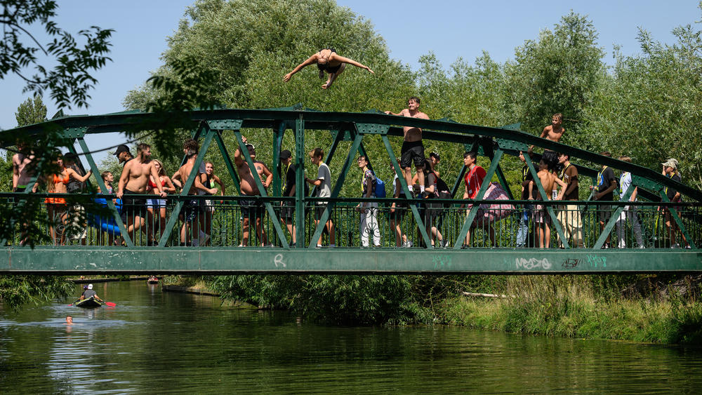 A woman does a backflip into the River Cam in Cambridge, England, on Monday, the first of two days on which temperatures are expected to hit record highs.
