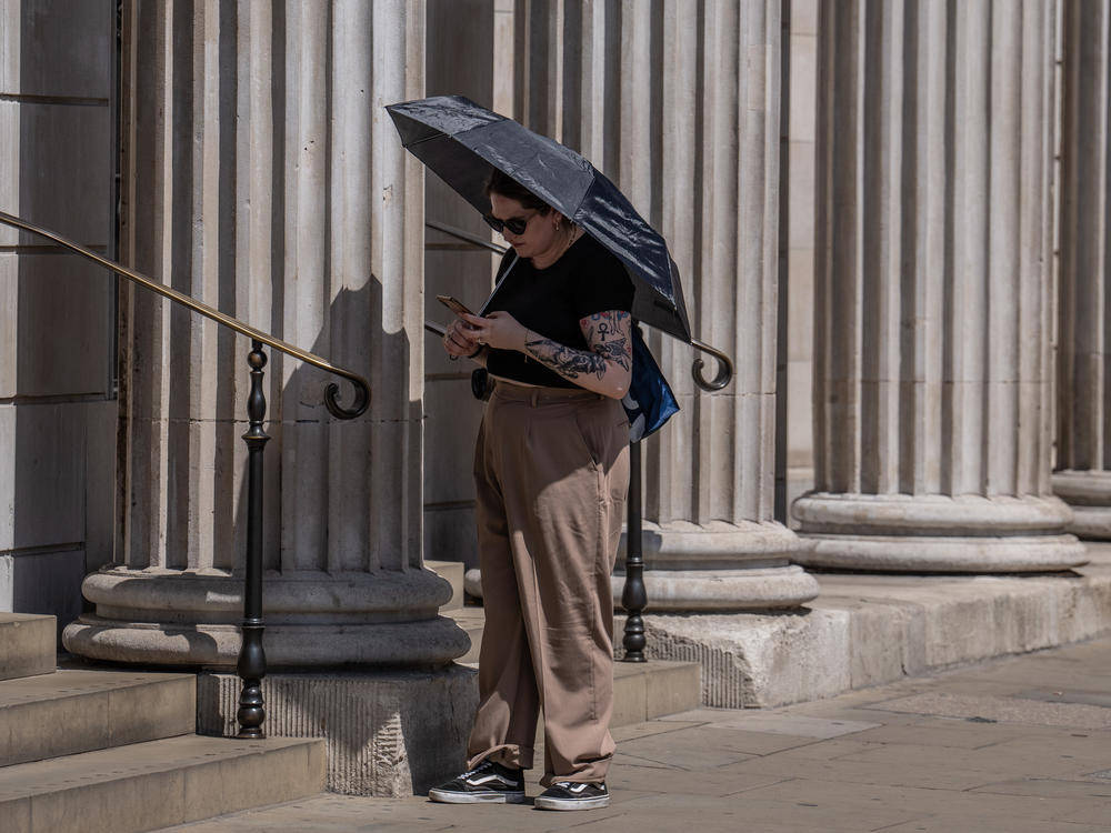 A woman shelters from the sun under a dark umbrella in London on Monday. Temperatures are forecast to hit well over 100 degrees in parts of the U.K. on Monday and Tuesday.