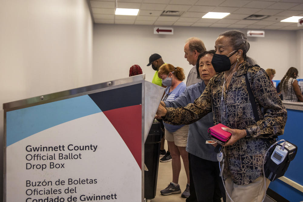 Gwinnett County voter Marian McCray (right) receives help from a poll worker while dropping off her absentee ballot at the Gwinnett County Board of Voter Registrations and Elections, in Lawrenceville, Ga., on May 18.